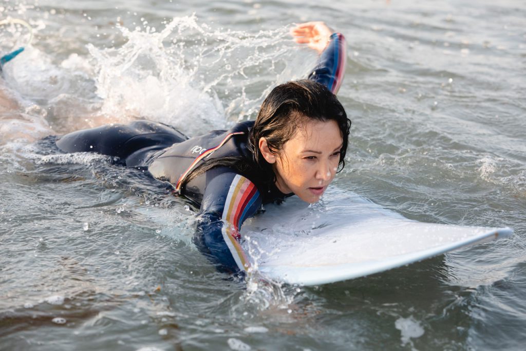 woman paddling in the ocean on surfboard